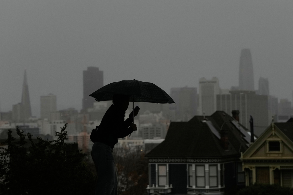 A pedestrian carries an umbrella while walking on a path at Alamo Square Park, in San Francisco, Tuesday, Dec. 23, 2025. (AP Photo/Jeff Chiu)