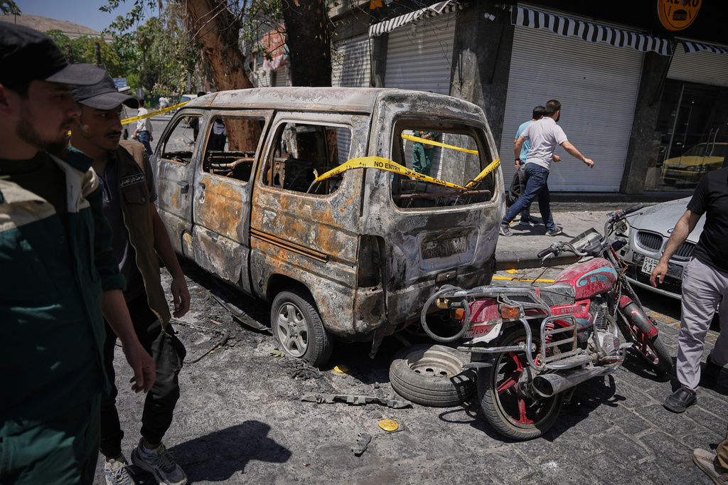 Syrian security personnel inspect a burned vehicles near the Four Seasons Hotel after two explosions rocked the area earlier while Syrian President Ahmad al-Sharaa was meeting French President Emmanuel Macron at the presidential palace, in Damascus, Syria, Tuesday, July 7, 2026. (AP Photo/Omar Albam)