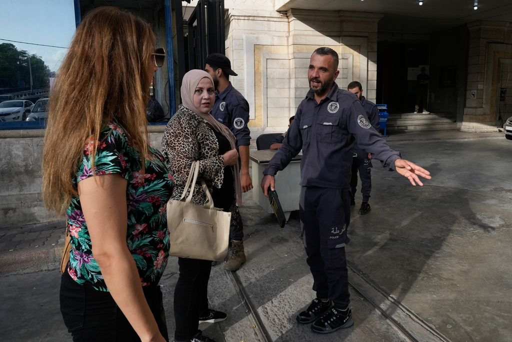 A Syrian policeman checks women at the entrance of Latakia's Governor building where the voting for a parliamentary election is taking place, in the coastal city of Latakia, Syria, Sunday, Oct. 5, 2025. (AP Photo/Hussein Malla)