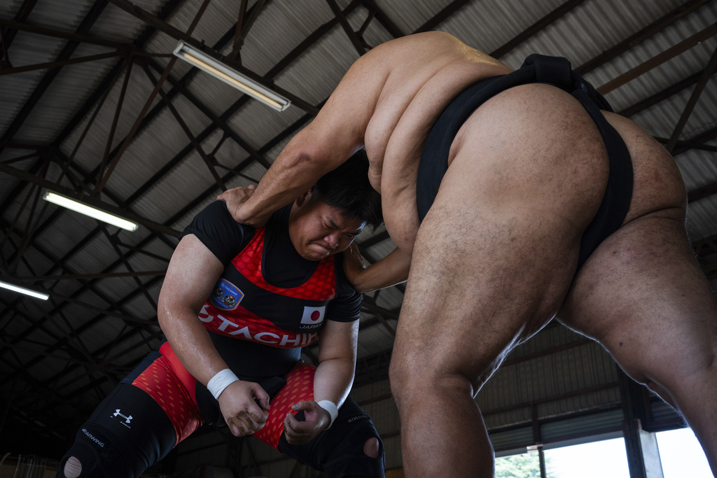 Airi Hisano and coach Toyonoshima Daiki train during a practice session at the Tachihi Holdings Women's sumo club in Tokyo, on Aug. 2, 2025. (AP Photo/Louise Delmotte)