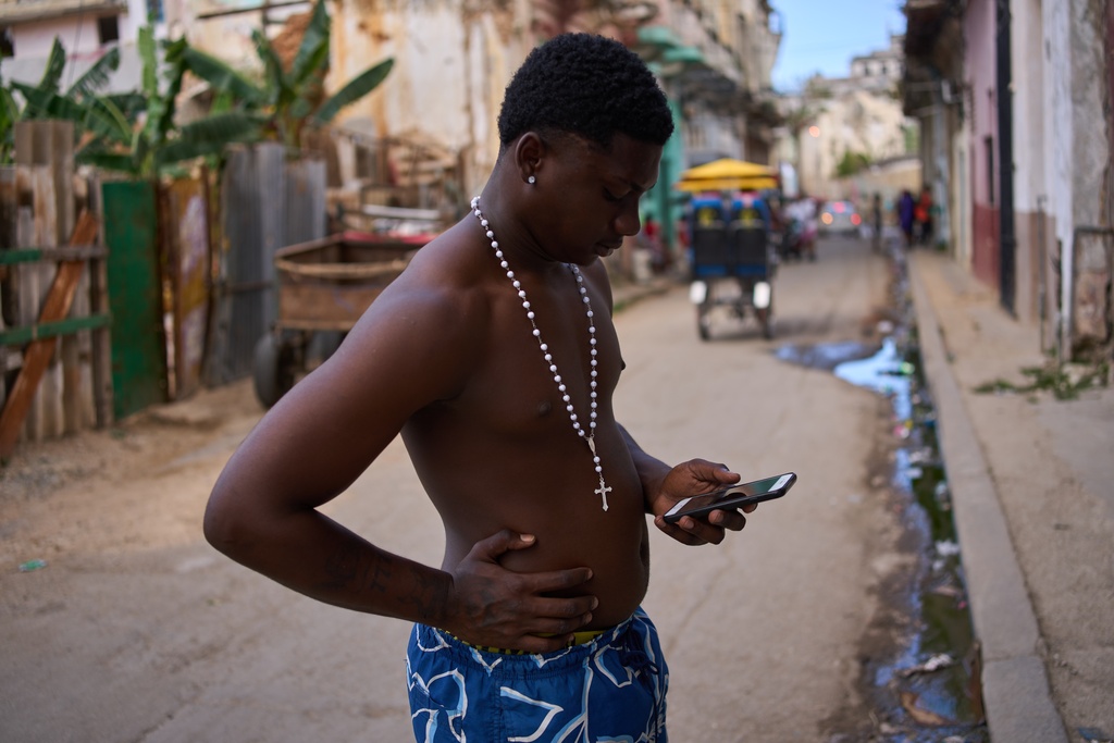 A man wearing a rosary looks at his phone during a blackout in Havana, Cuba, Thursday, March 5, 2026. (AP Photo/Ramon Espinosa)