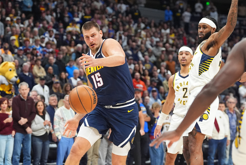 Denver Nuggets center Nikola Jokić, left, pursues a loose ball with Indiana Pacers forward Isaiah Jackson in the first half of an NBA basketball game Saturday, Nov. 8, 2025, in Denver. (AP Photo/David Zalubowski)