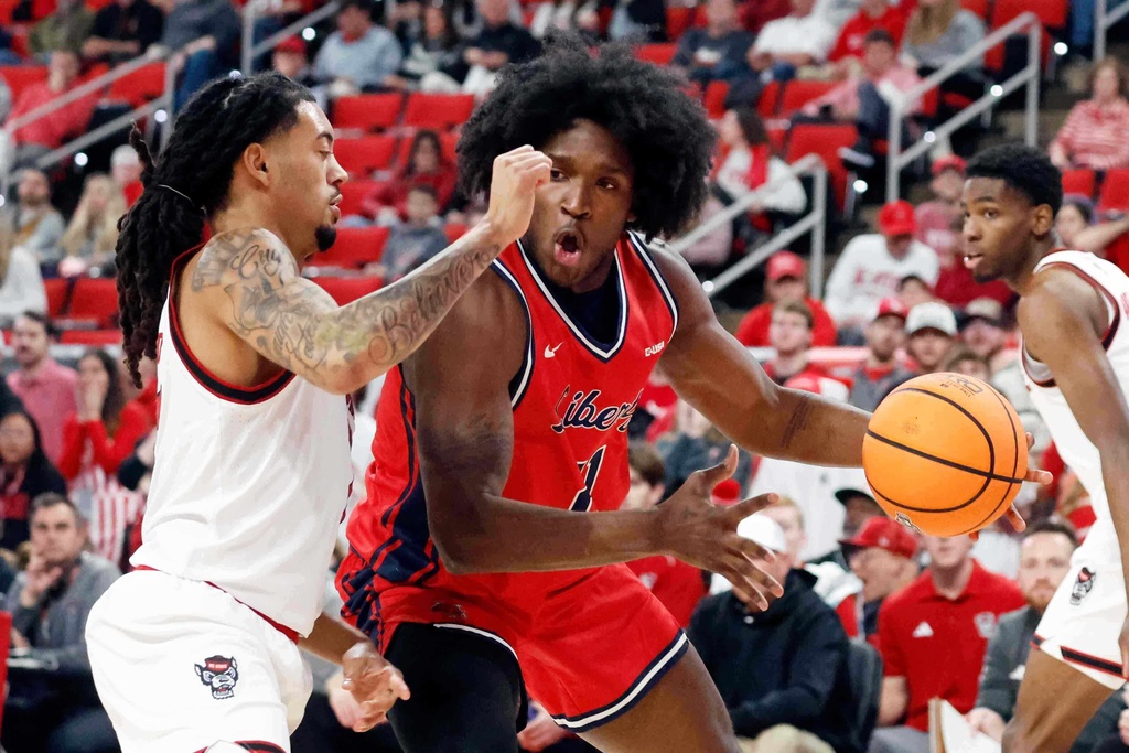 Liberty's Ryan Jones Jr. (21) controls the ball in a battle with North Carolina State's Alyn Breed (7) during the first half of an NCAA college basketball game in Raleigh, N.C., Wednesday, Dec. 10, 2025. (AP Photo/Karl DeBlaker)