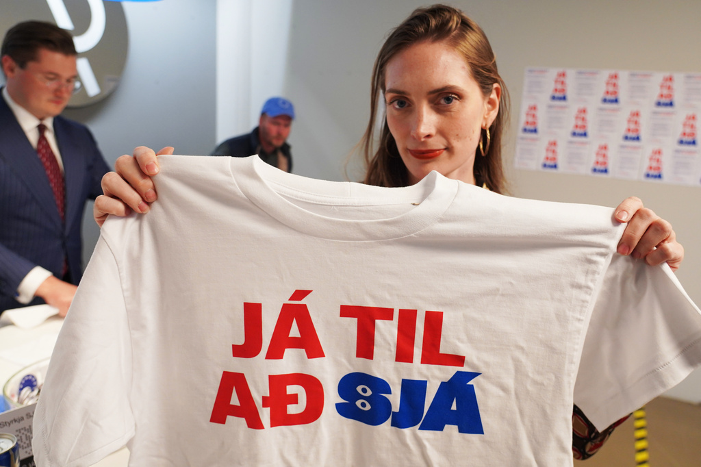 A supporter holds a t-shirt reading, "Yes to see", at the opening of the "Yes" campaign's office in Reykjavik, Iceland, Friday, Aug. 7, 2026. (AP Photo/James Brooks)