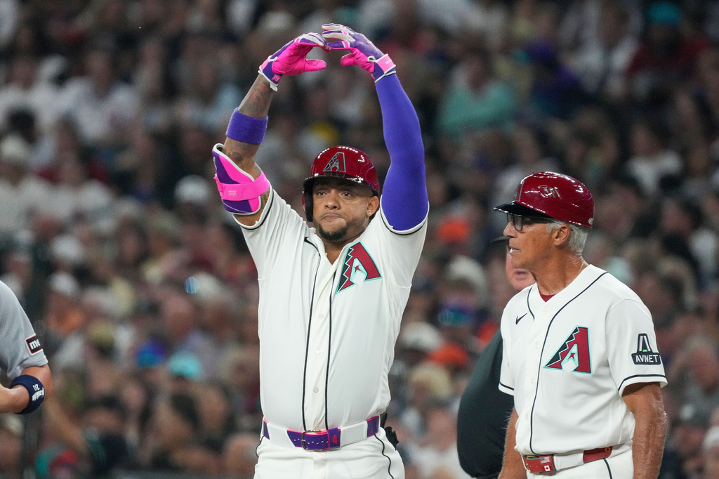 Arizona Diamondbacks first base coach Dave McKay, right, looks on Ketel Marte gestures after hitting a single against the Detroit Tigers during the first inning of an opening-day baseball game Monday, March 30, 2026, in Phoenix. (AP Photo/Darryl Webb)