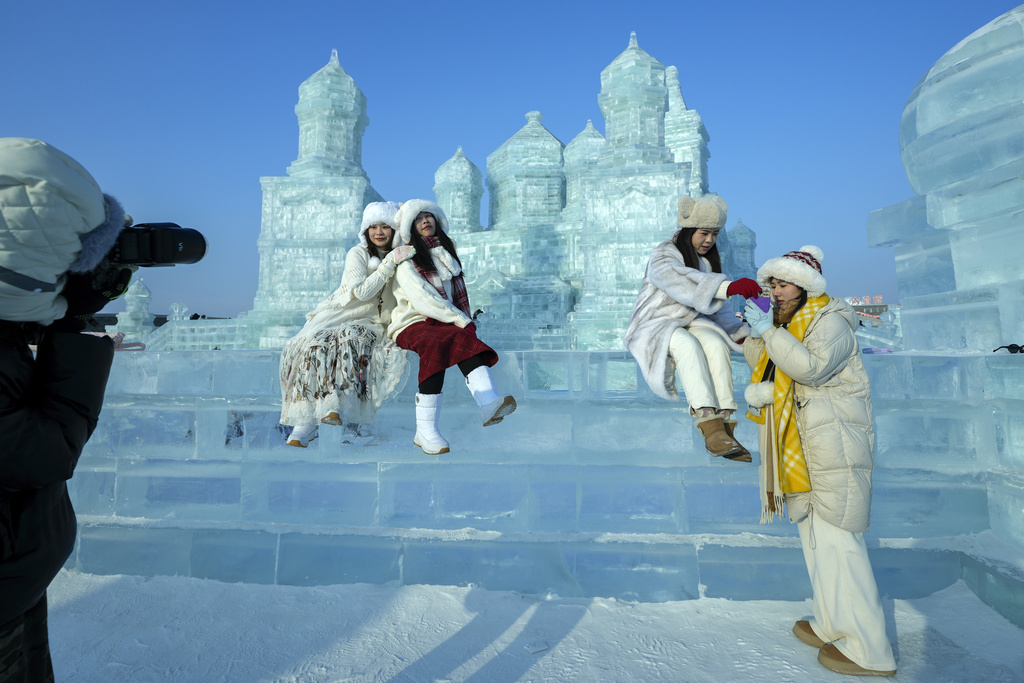 Visitors take souvenir pictures with the ice structures during the Harbin Ice and Snow World in Harbin, China's Heilongjiang province on Monday, Jan. 6, 2025. (AP Photo/Andy Wong)