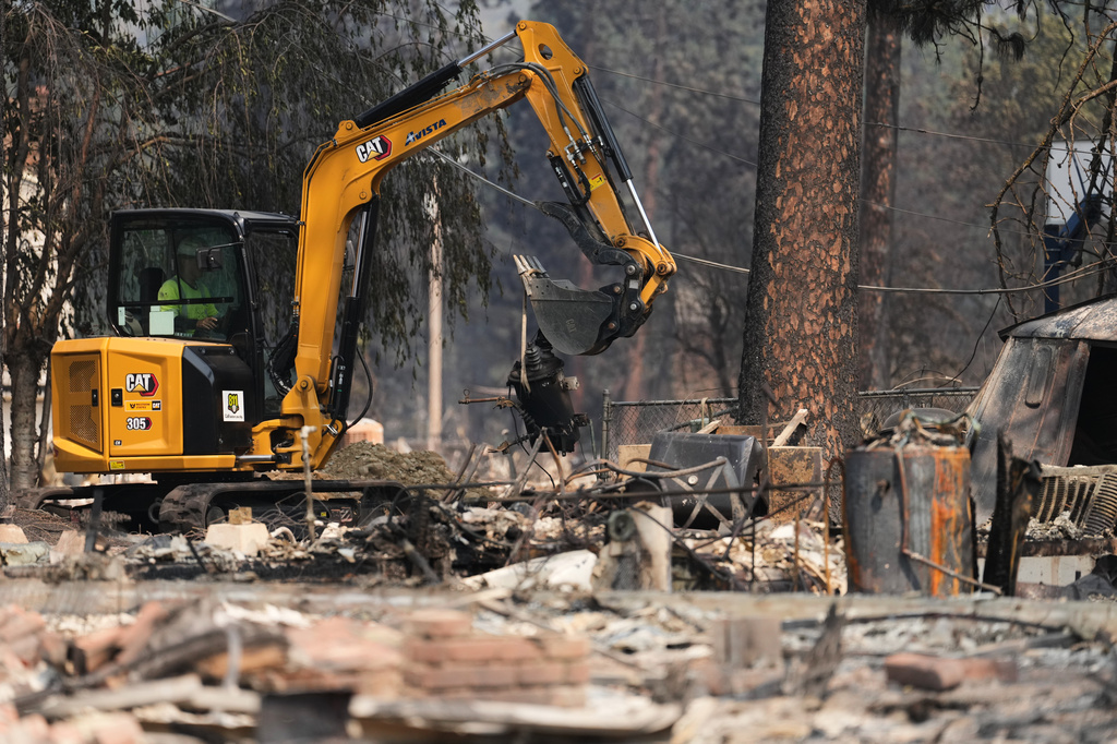 Crews work near several burned down houses after a wildfire hit the northwest part of Spokane, Wash., Tuesday, Aug. 4, 2026. (AP Photo/Lindsey Wasson)