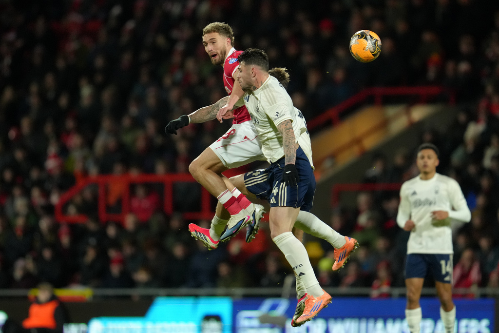Wrexham's Sam Smith, left, and Nottingham Forest's Morato challenge for the ball during the English FA Cup third round soccer match between Wrexham and Nottingham Forest in Wrexham, Wales, Friday, Jan. 9, 2026. (AP Photo/Jon Super)