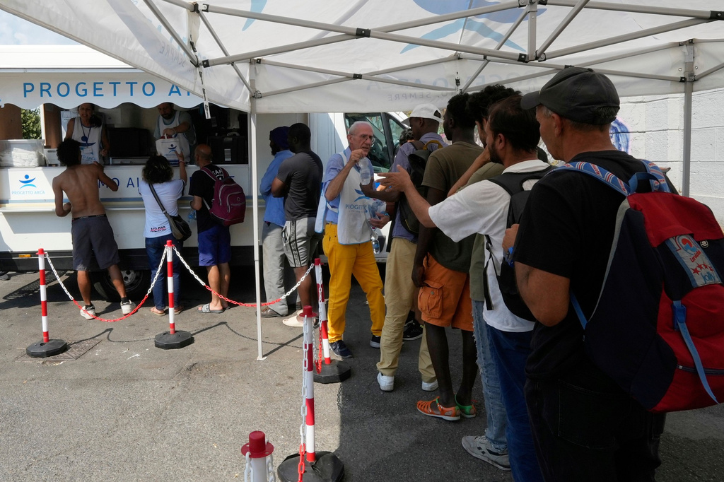 FILE - Volunteers distribute food and water to homeless people at the Progetto Arca Onlus foundation volunteer shelter, in Milan, Italy, July 3, 2025. (AP Photo/Luca Bruno, File)