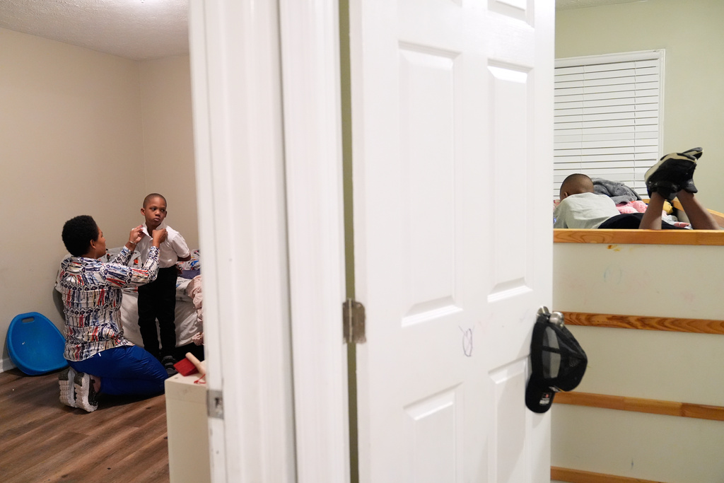 Sechita McNair helps Derrick McNair-White get ready for school while Malachi McNair-Nesbitt watches a video early in the morning on Aug. 4, 2025, in Jonesboro, Ga. (AP Photo/Brynn Anderson)