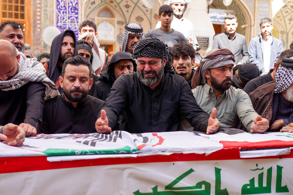 Relatives pray near the coffin of an Iranian-backed Popular Mobilization Forces fighter killed in recent airstrikes on Qaim, Tuesday, March 17, 2026. in Najaf, Iraq. (AP Photo/Anmar Khalil)