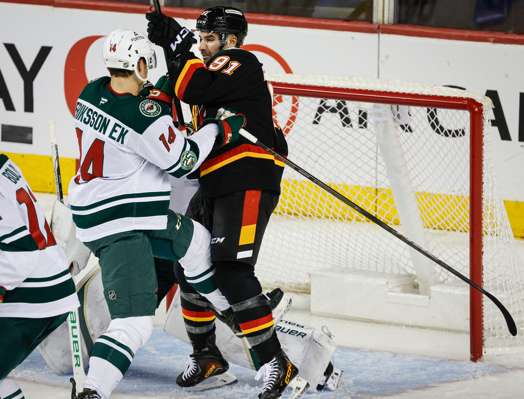 Minnesota Wild's Joel Eriksson Ek, left, pushes Calgary Flames' Nazem Kadri in front of the net during second period NHL hockey action in Calgary on Thursday, Dec. 4, 2025. (Jeff McIntosh/The Canadian Press via AP)