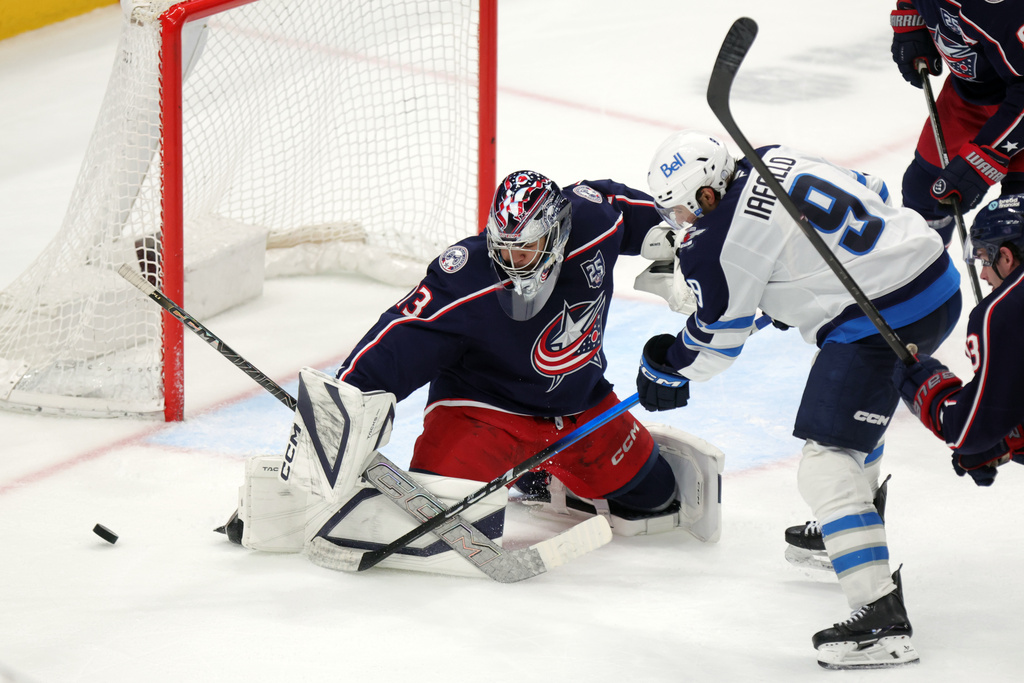 Columbus Blue Jackets goalie Jet Greaves, left, stops a shot in front of Winnipeg Jets forward Alex Iafallo during the third period of an NHL hockey game in Columbus, Ohio, Saturday, April 4, 2026. (AP Photo/Paul Vernon)