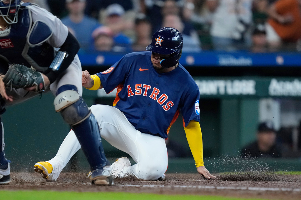 Houston Astros' Isaac Paredes, right, scores behind New York Yankees catcher J.C. Escarra, left, on a double by Astros' Christian Walker during the fifth inning of a baseball game Sunday, April 26, 2026, in Houston. (AP Photo/Kevin M. Cox)