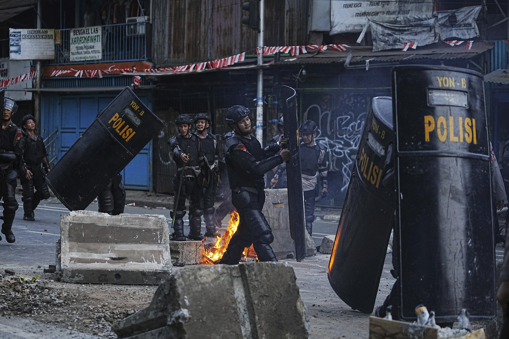 Riot police officers carry their shields as they take their position during a protest against lavish allowances given to parliament members, in Jakarta, Indonesia, Monday, Aug. 25, 2025. (AP Photo/Achmad Ibrahim)