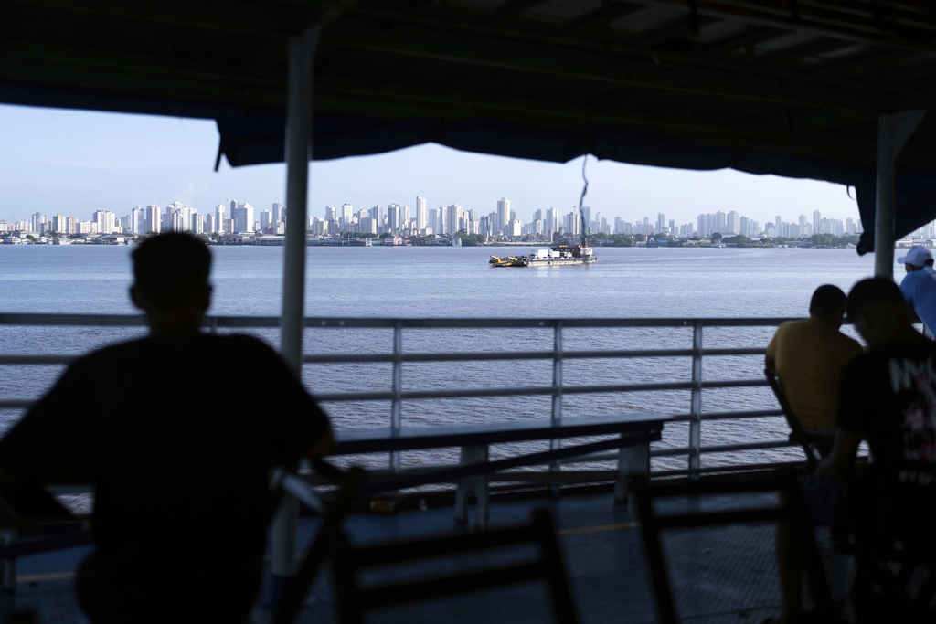 FILE - People look out at the coast of Belem, Brazil, as a boat nears shore, March 23, 2025. (AP Photo/Jorge Saenz, File)