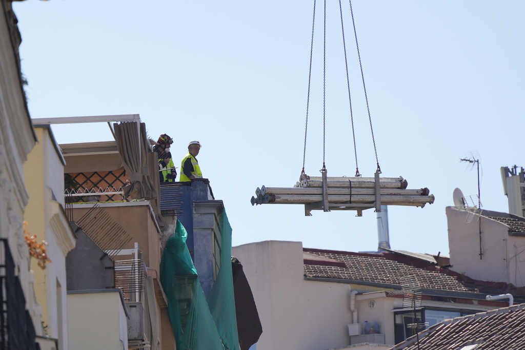Rescue workers stand on the roof at the scene of a building collapse in Madrid, Spain, on Tuesday, Oct. 7, 2025. (AP Photo/Manu Fernandez)