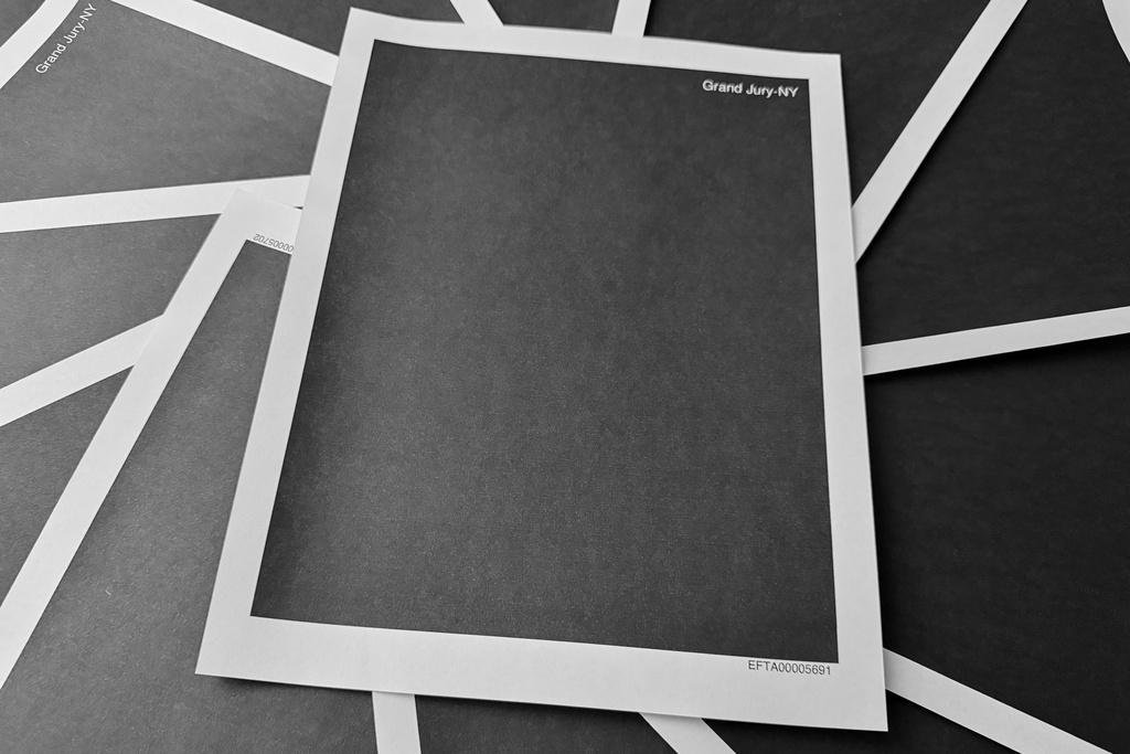 Pages from a totally redacted New York grand jury file into Jeffrey Epstein and Ghislaine Maxwell, released by the U.S. Justice Department, is photographed Friday, Dec. 19, 2025, in Washington. (AP Photo/Jon Elswick)