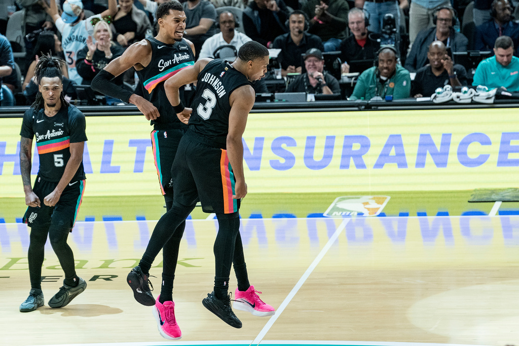 San Antonio Spurs forward Victor Wembanyama (1) and San Antonio Spurs forward Keldon Johnson (3) celebrate Johnson's basket against the Oklahoma Thunder during the second half of an NBA basketball game in San Antonio, Tuesday, Dec. 23, 2025. (AP Photo/Rodolfo Gonzalez)