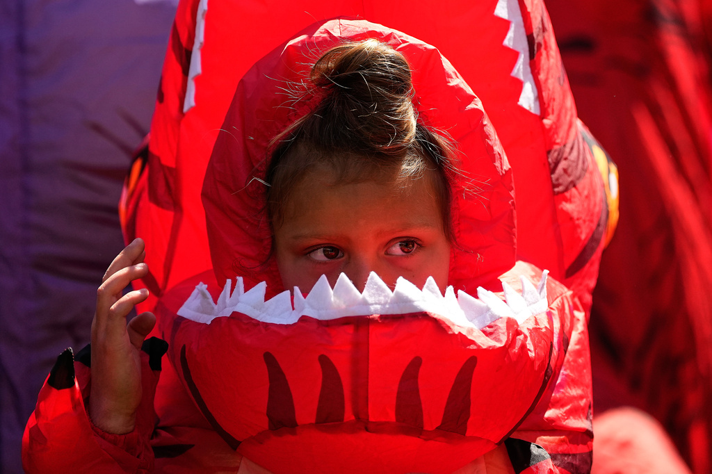 Tilly Sawangwan, 5, looks on in a red costume during the T-Rex World Championship Races at Emerald Downs, Sunday, July 12, 2026, in Auburn, Wash. (AP Photo/Lindsey Wasson)