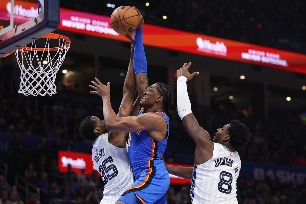 Oklahoma City Thunder guard Jalen Williams, center, goes up to dunk against Memphis Grizzlies center Christian Koloko (35) and forward Jaren Jackson Jr. (8)during the second half of an NBA basketball game Monday, Dec. 22, 2025, in Oklahoma City. (AP Photo/Nate Billings)