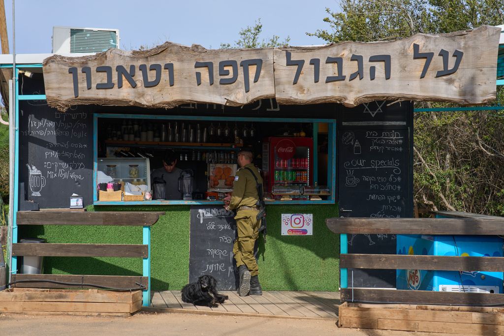 An Israeli soldier orders drinks from a coffee shop in northern Israel, on the border with Lebanon following a ceasefire between Israel and Hezbollah, Friday, April 17, 2026. Signage in Hebrew reads, "Coffee on the border."(AP Photo/Ariel Schalit)