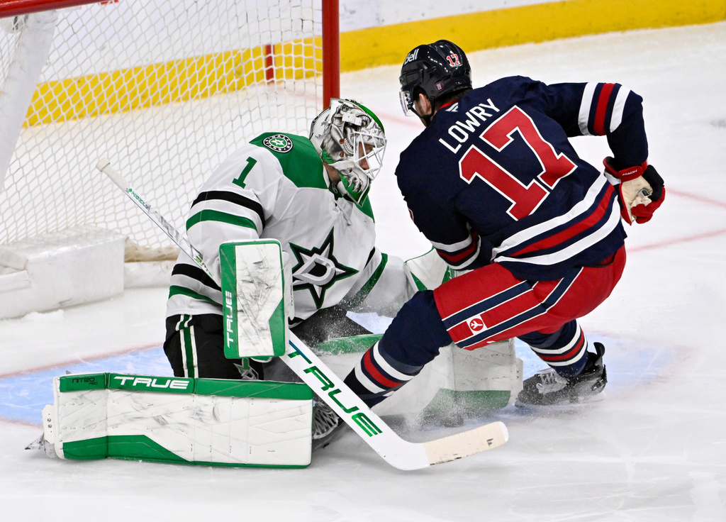 Dallas Stars' goaltender Casey DeSmith (1) makes a save on Winnipeg Jets' Adam Lowry (17) during the third period of their NHL hockey game in Winnipeg, Tuesday, Dec. 9, 2025. (Fred Greenslade/The Canadian Press via AP)