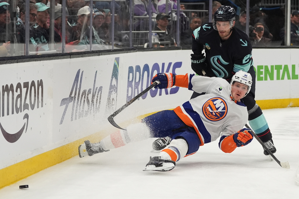 New York Islanders center Kyle MacLean, front, falls against Seattle Kraken defenseman Jamie Oleksiak, back, during the second period of an NHL hockey game Wednesday, Jan. 21, 2026, in Seattle. (AP Photo/Lindsey Wasson)