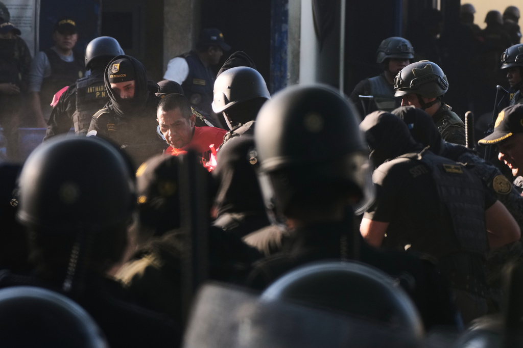 Security forces escort an inmate after entering the Renovation maximum-security prison to free guards taken hostage and retake control of the facility, which houses gang leaders, in Escuintla, Guatemala, Sunday, Jan. 18, 2026. (AP Photo/Moises Castillo)
