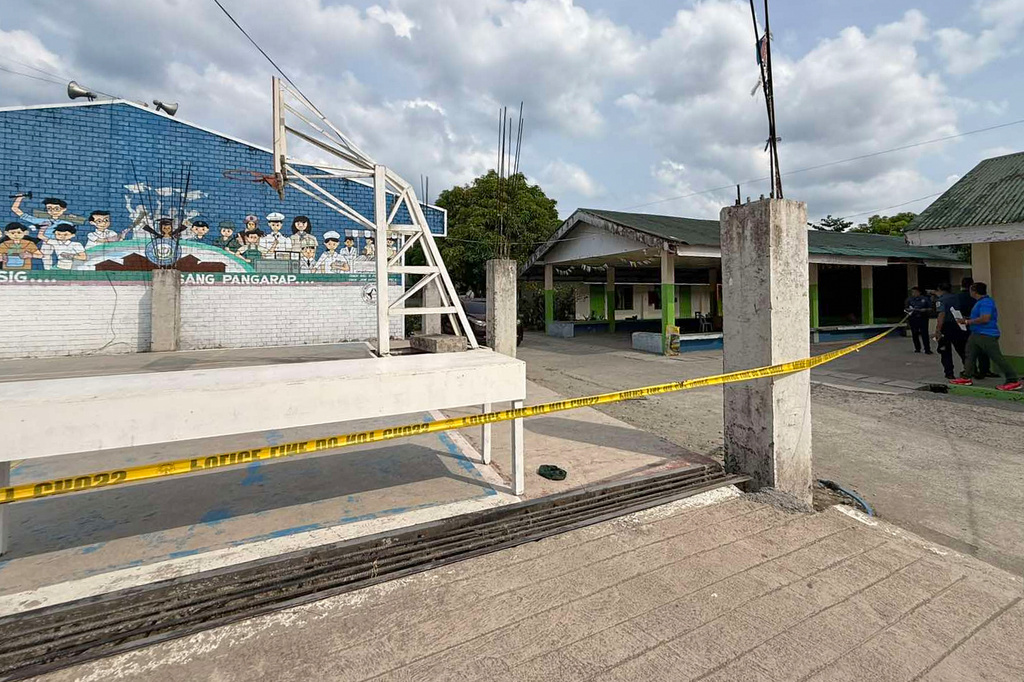 In this photo provided by the Tacloban City Police Office, police stand outside the San Jose National High School after the area was cordoned off following a shooting incident inside the school, in Tacloban city, central Philippines, Monday June 22, 2026. (Tacloban City Police Office via AP)