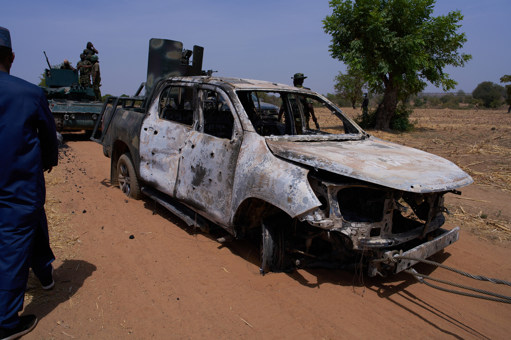 In this photo released by the Kebbi State Government, a man inspects a burned military vehicle following a late Tuesday ambush by armed militants in Shanga, Kebbi, northern Nigeria, Wednesday, March. 25, 2026. (Kebbi State Government via AP)