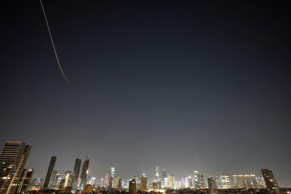 Missiles launched from Iran streak across the sky over central Israel, early Tuesday, March 24, 2026. (AP Photo/Ohad Zwigenberg)