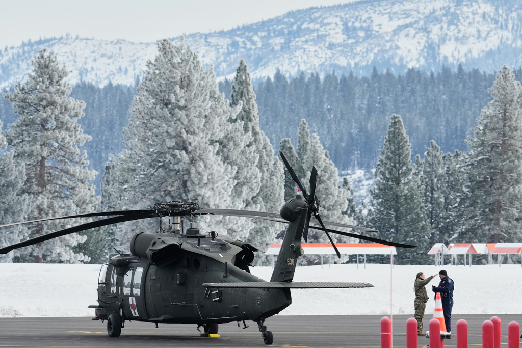 A member of the U.S. Army and a member of the California Highway Patrol speak on the runway at the Truckee Tahoe Airport as recovery efforts for a group of missing skiers continue in Truckee, Calif., Saturday, Feb. 21, 2026. (AP Photo/Godofredo A. Vásquez)