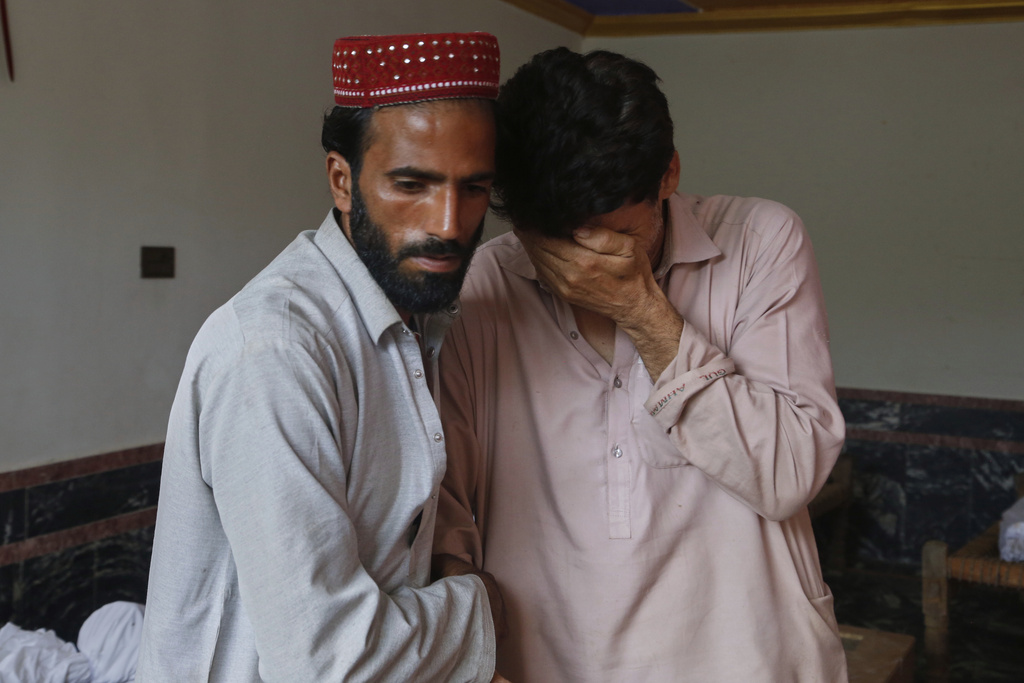 Two men comfort each other as they mourn over the death of their family member in Friday's flash flooding, at a village near Pir Baba, Buner district, in Pakistan's northwest, Saturday, Aug.16, 2025. (AP Photo/Muhammad Sajjad)