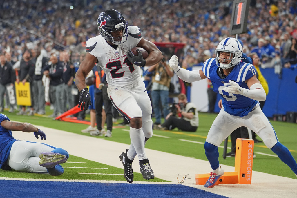 Houston Texans running back Nick Chubb (21) rushes for a touchdown as Indianapolis Colts' Camryn Bynum (0) defends during the first half of an NFL football game Sunday, Nov. 30, 2025, in Indianapolis. (AP Photo/Michael Conroy)