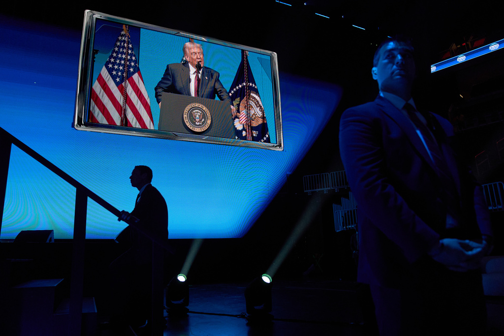 President Donald Trump is seen speaking on a screen as Secret Service Agents stand watch, during a speech to the America Business Forum, at the Kaseya Center, Wednesday, Nov. 5, 2025, in Miami. (AP Photo/Jacquelyn Martin)