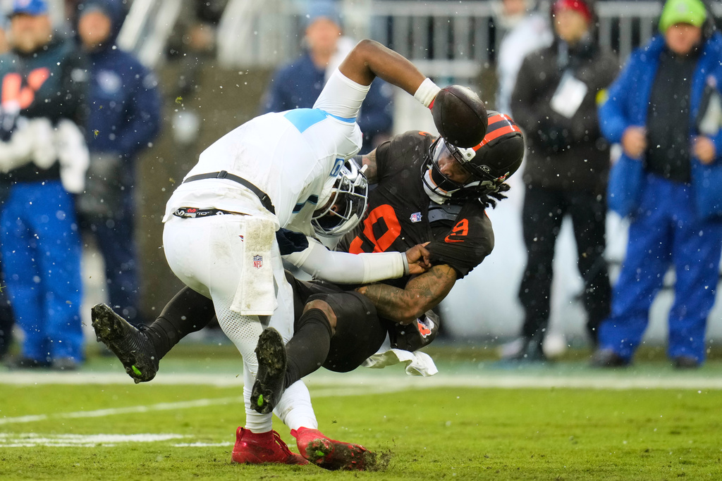 Tennessee Titans quarterback Cam Ward (1) fights off a tackle attempt by Cleveland Browns safety Grant Delpit (9) in the second half of an NFL football game in Cleveland, Sunday, Dec. 7, 2025. (AP Photo/Sue Ogrocki)