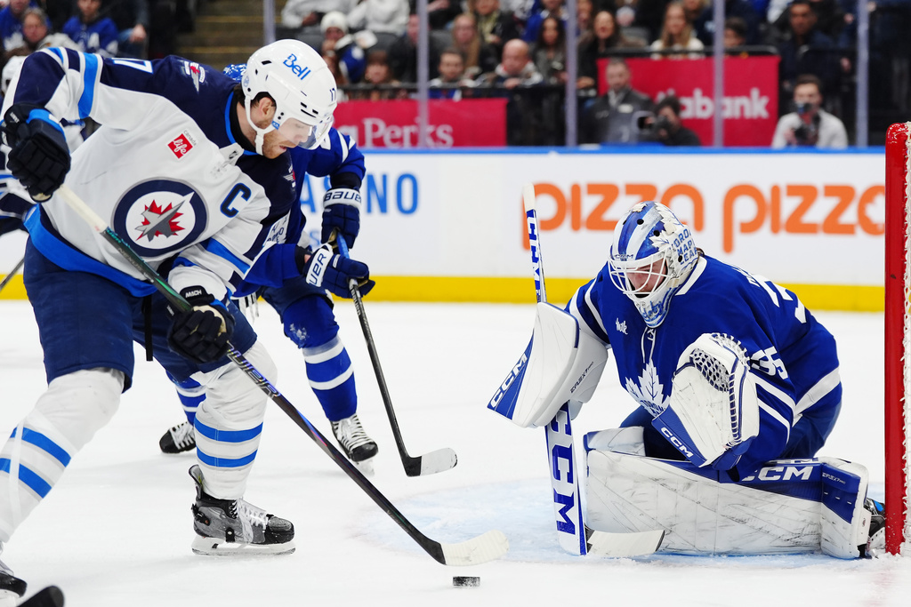 Toronto Maple Leafs goaltender Dennis Hildeby, right, stops Winnipeg Jets' Adam Lowry during the third period of an NHL hockey game in Toronto, Thursday, Jan. 1, 2026. (Frank Gunn/The Canadian Press via AP)