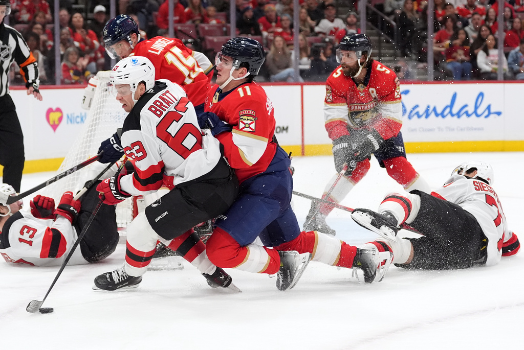 New Jersey Devils left wing Jesper Bratt (63) comes under pressure from Florida Panthers right wing Mackie Samoskevich (11) alongside the Panthers goal during the first period of an NHL hockey game, Thursday, Nov. 20, 2025, in Sunrise, Fla. (AP Photo/Rebecca Blackwell)