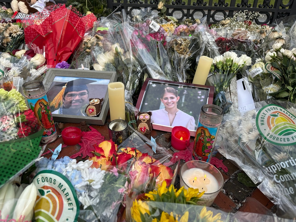 Flowers and candles surround photos of Mukhammad Aziz Umurzokov, an 18-year-old freshman from Brandermill, Va., and Ella Cook, a 19-year-old sophomore from a suburb of Birmingham, Ala., in front of a Brown University gate in Providence, R.I., on Wednesday, Dec. 17, 2025. (AP Photo/Leah Willingham)