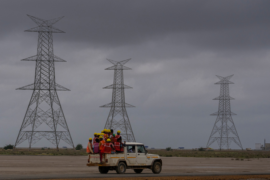FILE - Workers travel in a vehicle toward the construction site of Adani Green Energy Limited's Renewable Energy Park in the salt desert of Karim Shahi village, near Khavda, Bhuj district near the India-Pakistan border in the western state of Gujarat, India, on Sept. 21, 2023. (AP Photo/Rafiq Maqbool, File)