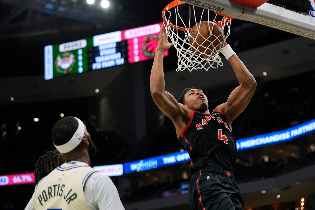 Toronto Raptors' Scottie Barnes (4) dunks past Milwaukee Bucks' Bobby Portis during the first half of an NBA basketball game, Thursday, Dec. 18, 2025, in Milwaukee. (AP Photo/Aaron Gash)