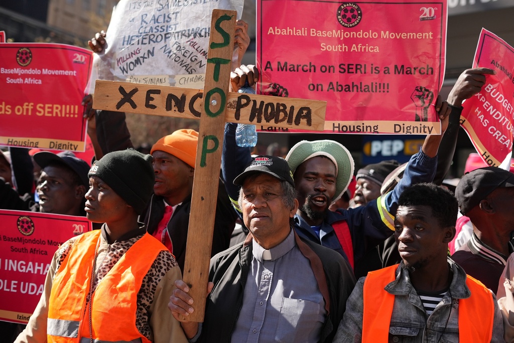 A pastor holds a wooden cross during an anti-xenophobia march in Johannesburg, South Africa, Thursday, July 17, 2025,(AP Photo/Alfonso Nqunjana)
