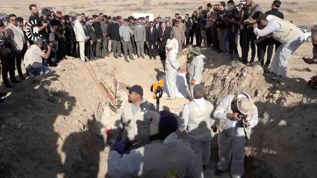 In this image taken from video provided by Rudaw TV, workers dig out human remains at the Khasfa site near the northern Iraqi city of Mosul, where authorities have begun excavating a mass grave believed to contain thousands of victims of the Islamic State (IS) Mosul, Iraq, Sunday, Aug. 17, 2025. (Rudaw TV via AP)