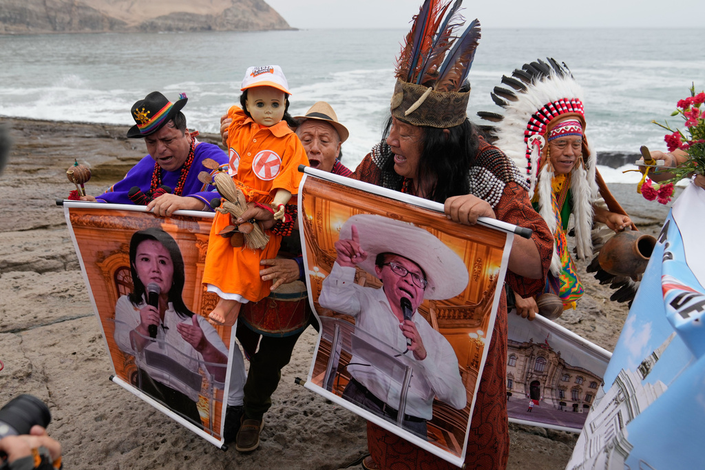 Shamans perform a ritual holding posters of presidential candidate Keiko Fujimori, left, and Roberto Sanchez on Herradura beach in Lima, Peru, Monday, June 1, 2026, ahead of their presidential runoff election. (AP Photo/Martin Mejia)