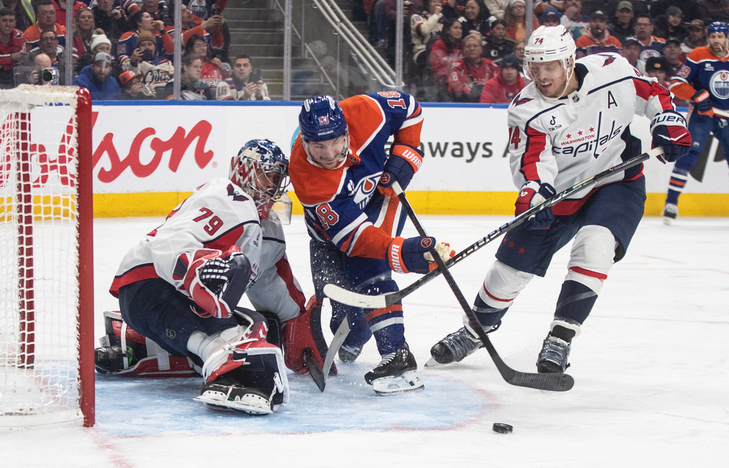 Washington Capitals' goalie Charlie Lindgren (79) makes a save against Edmonton Oilers' Zach Hyman (18) as Capitals' John Carlson (74) defends during second-period NHL hockey game action in Edmonton, Alberta, Saturday, Jan. 24, 2026. (Jason Franson/The Canadian Press via AP)