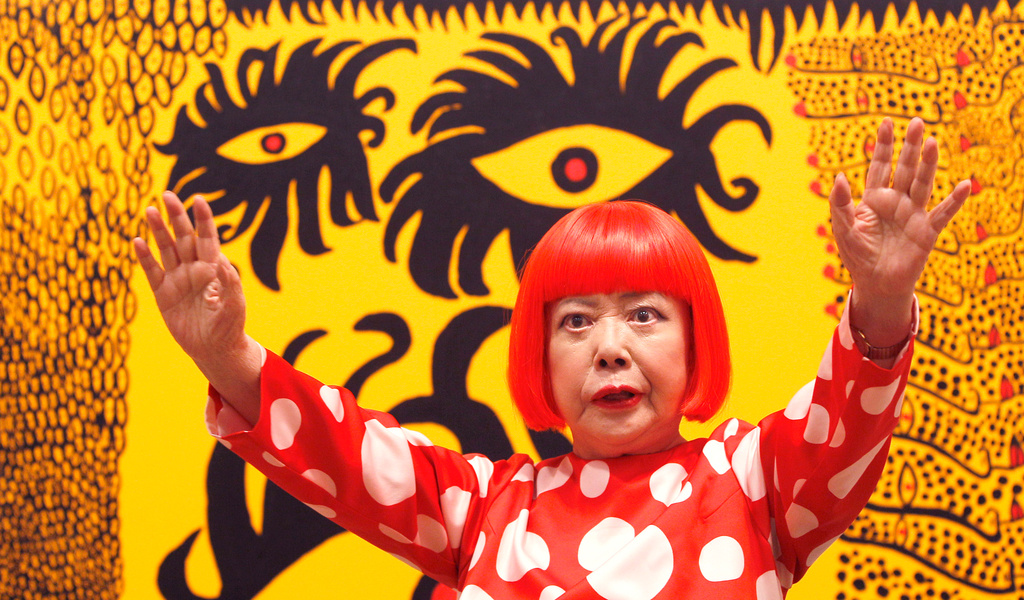 FILE - Japanese artist Yayoi Kusama poses for photographers in front of her painting "Love Arrives at the Earth Carrying with it a Tale of the Cosmos" at the Tate Modern in London, on Feb. 7, 2012. (AP Photo/Kirsty Wigglesworth, File)