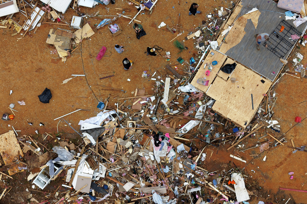 People walk among debris at Gene's Mobile Home Supply, a trailer park in Bogue Chitto, Miss., Thursday, May, 7, 2026, after a tornado cut across the state. (AP Photo/Gerald Herbert)