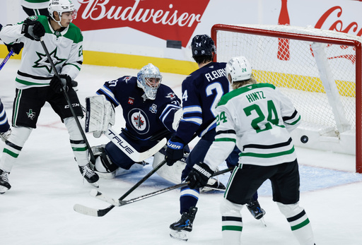 Dallas Stars' Jason Robertson (21) and Roope Hintz (24) look on as a shot by Nils Lundkvist (not shown) gets past Winnipeg Jets goaltender Connor Hellebuyck (37) during first-period NHL hockey game action in Winnipeg, Manitoba, Thursday, Oct. 9, 2025. (John Woods/The Canadian Press via AP) Dallas Stars' Jason Robertson (21) and Roope Hintz (24) look on as a shot by Nils Lundkvist (not shown) gets past Winnipeg Jets goaltender Connor Hellebuyck (37) during first-period NHL hockey game action in Winnipeg, Manitoba, Thursday, Oct. 9, 2025. (John Woods/The Canadian Press via AP)