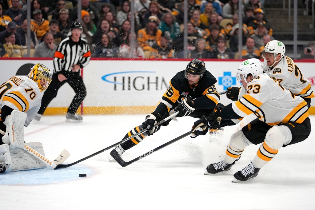 Pittsburgh Penguins' Erik Karlsson (65) can't get off a shot in front of Boston Bruins goaltender Joonas Korpisalo (70) with Hampus Lindholm (27) and Charlie McAvoy (73) defending during the second period of an NHL hockey game in Pittsburgh, Sunday, March 8, 2026. (AP Photo/Gene J. Puskar)